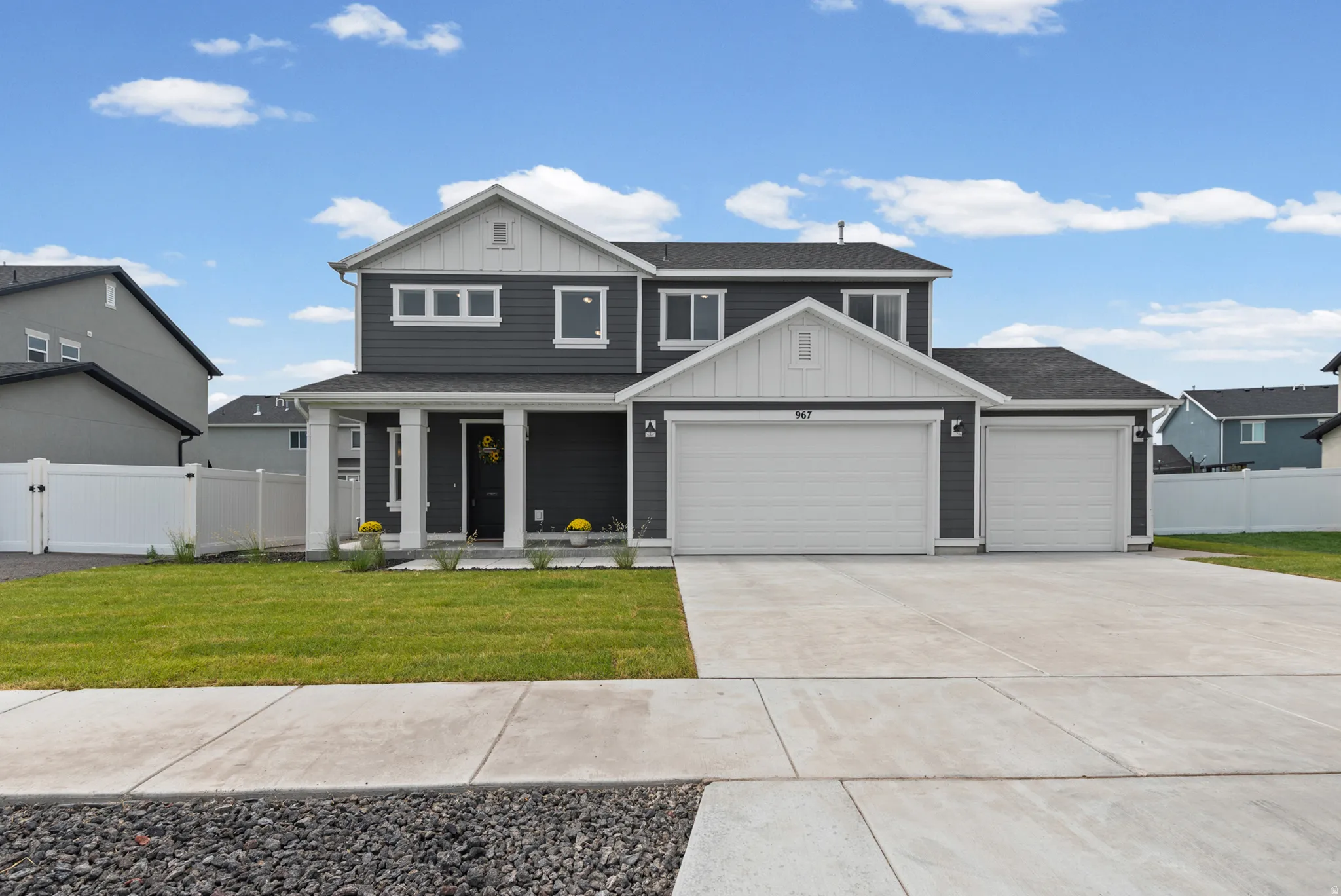 Modern two-story home featuring a charcoal and light gray exterior with board-and-batten siding, multiple gabled rooflines, and architectural detail