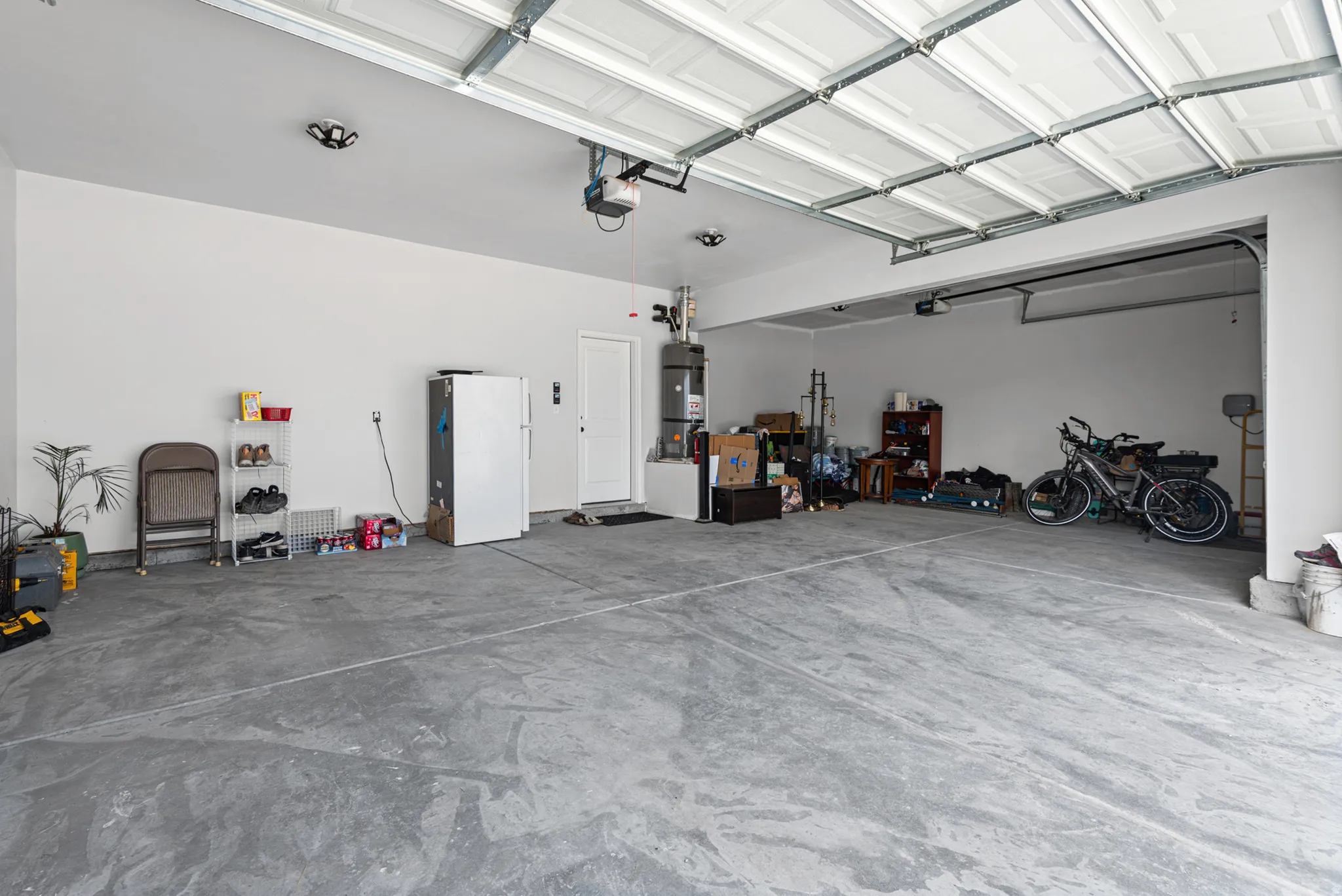 Attached dual garage with concrete flooring, overhead lighting, and white panel garage doors