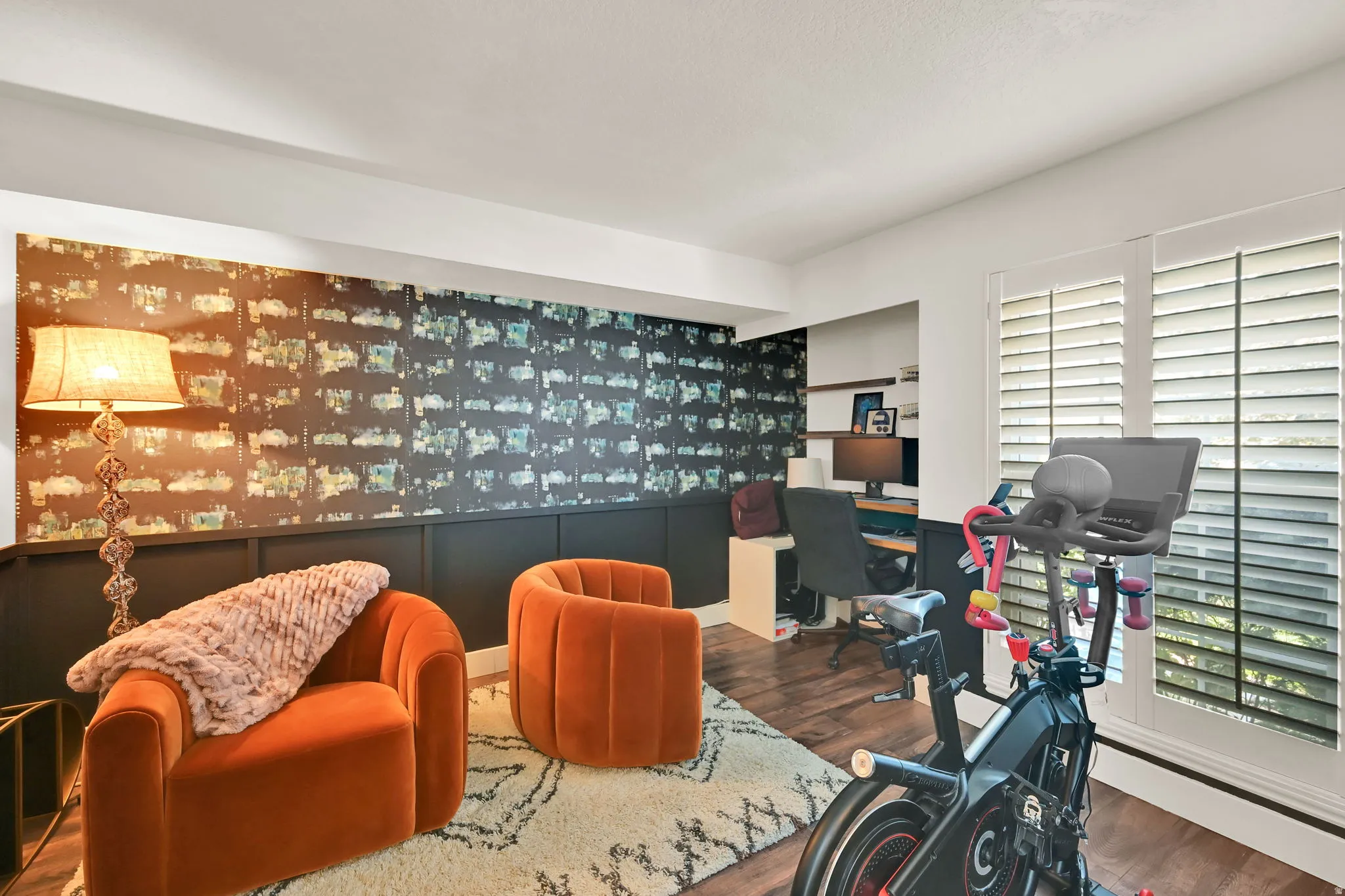 Modern home office and recreation space featuring vibrant orange upholstered seating, wood-finish flooring, and custom accent wall paneling with integrated lighting