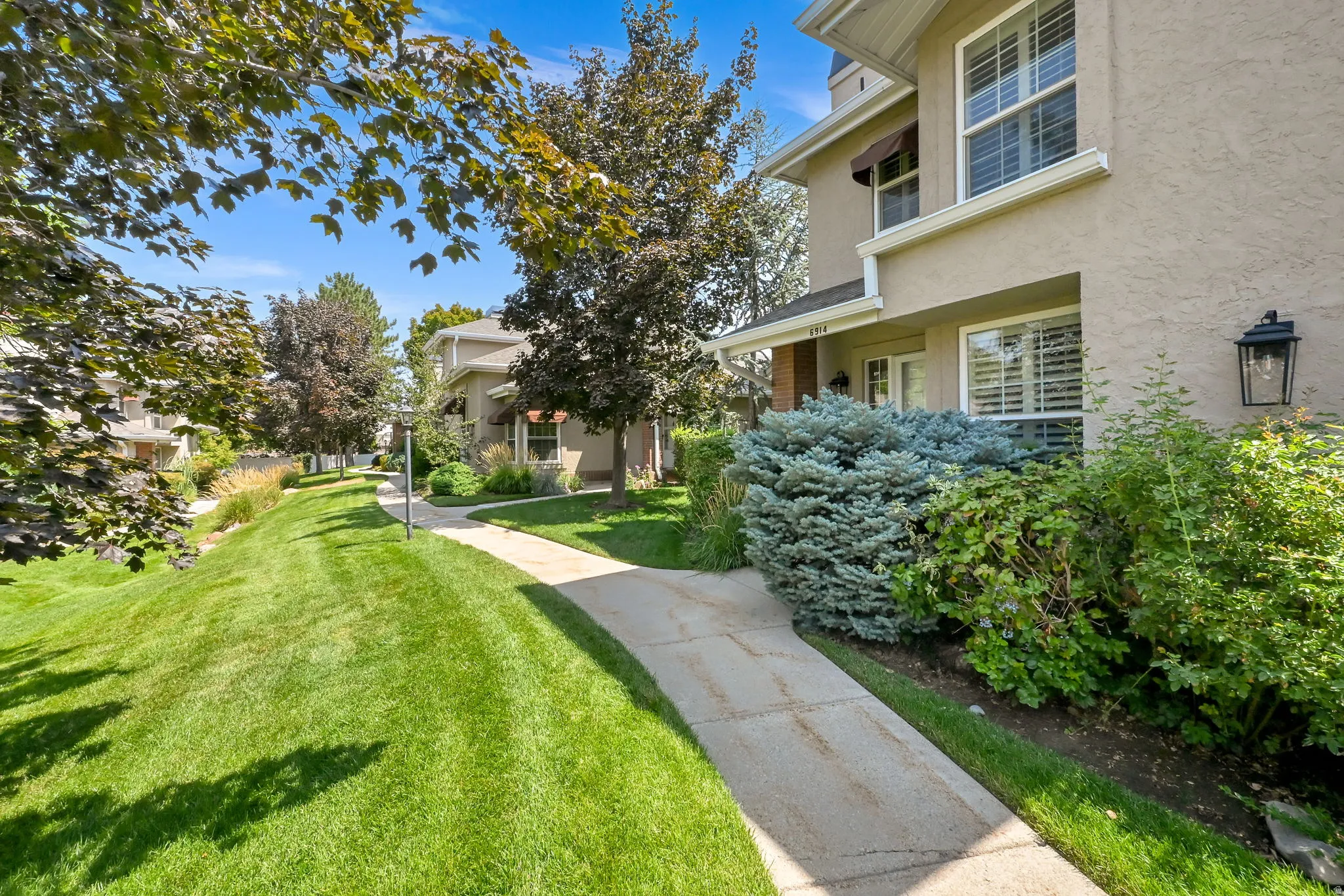 Manicured lawn with mature landscaping and stone walkway leading to the home's entrance