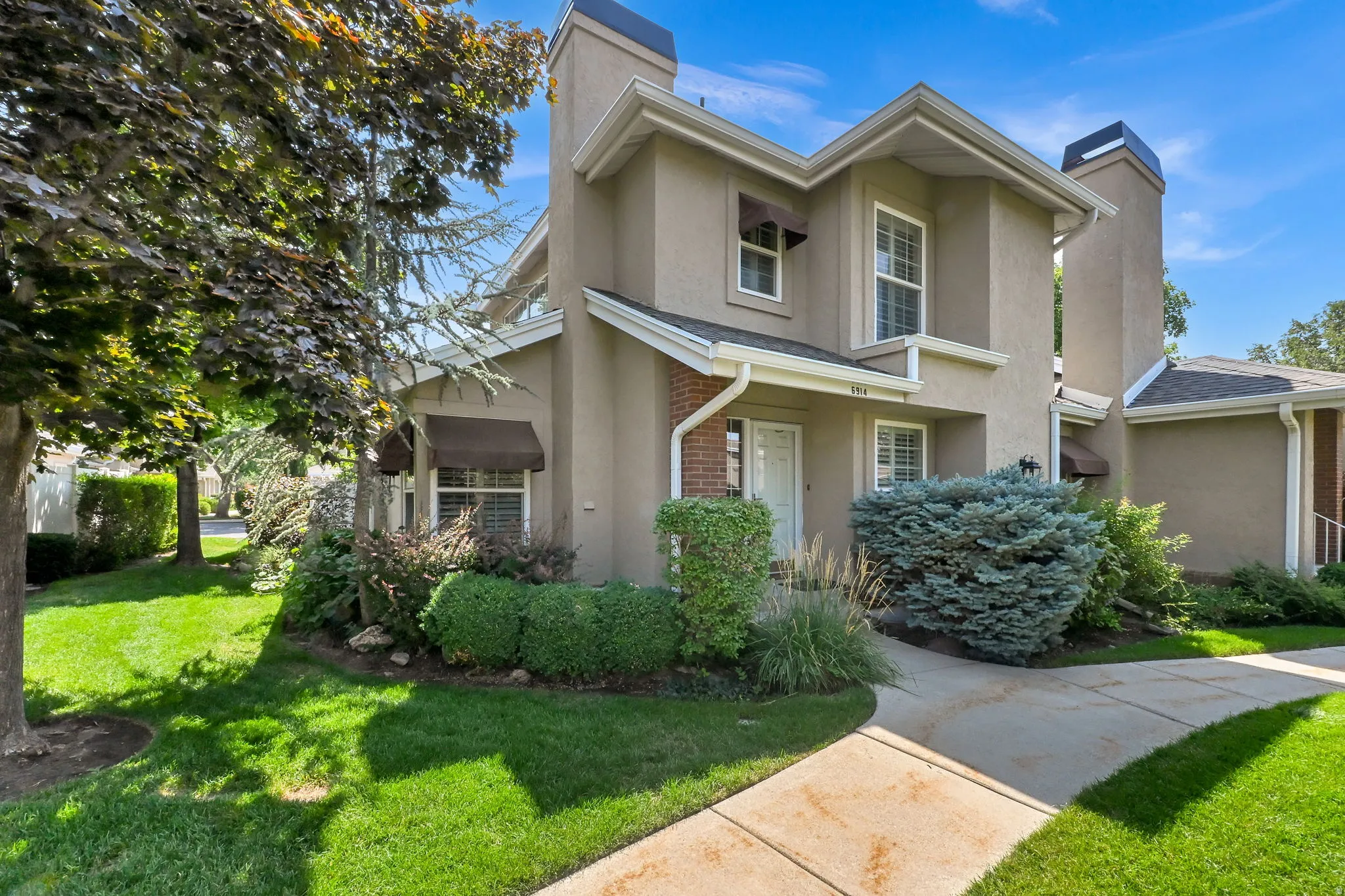 Stucco exterior with brick accents, multiple windows, and a paved walkway