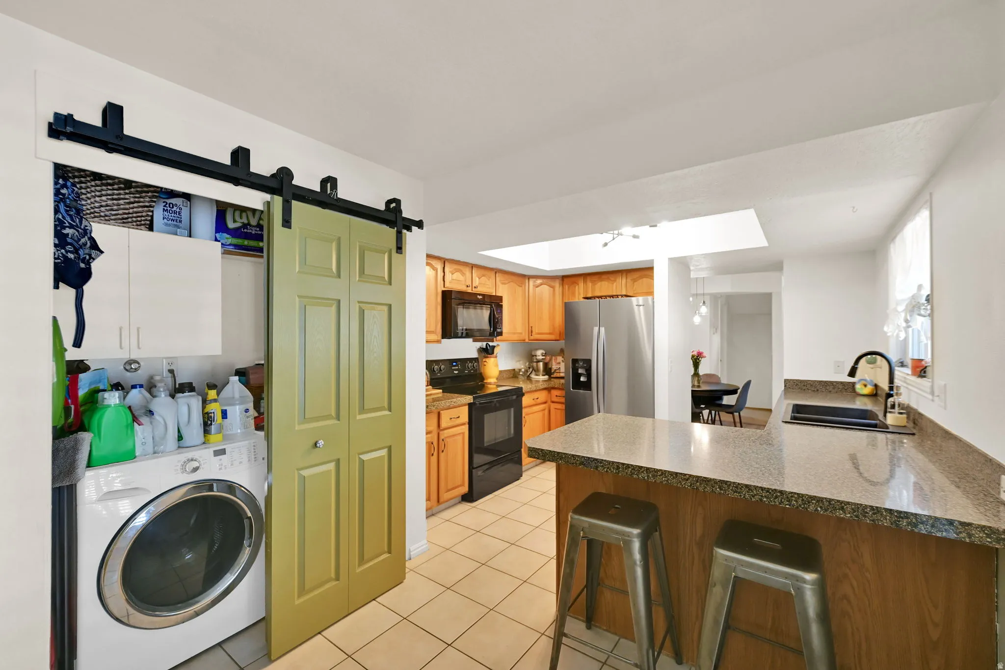 Kitchen featuring wood cabinetry, stainless steel appliances, and a breakfast bar with stone-look countertops