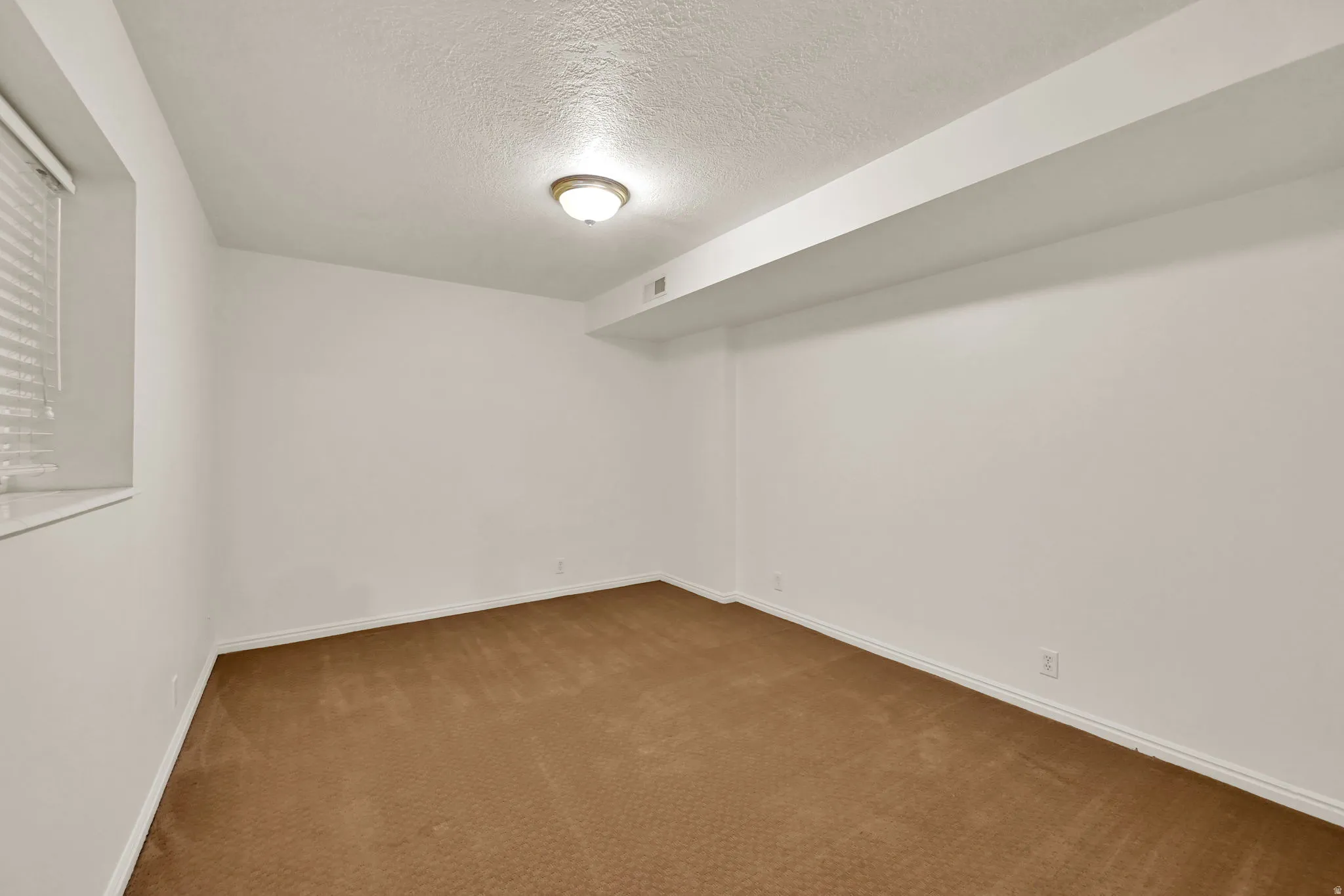 Spacious interior room featuring warm wood-finish flooring, clean white walls, and recessed ceiling lighting
