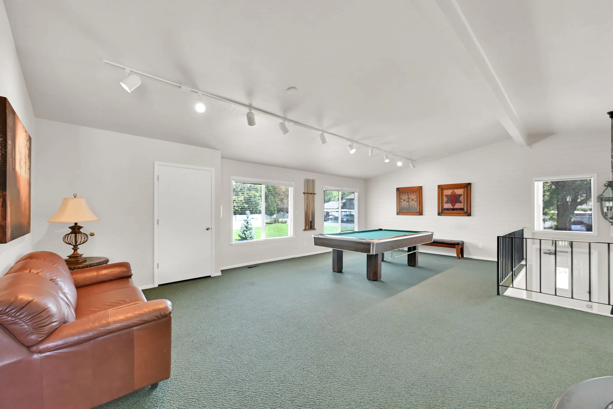 Spacious recreation room featuring track lighting, polished concrete flooring, and a wood-finish pool table