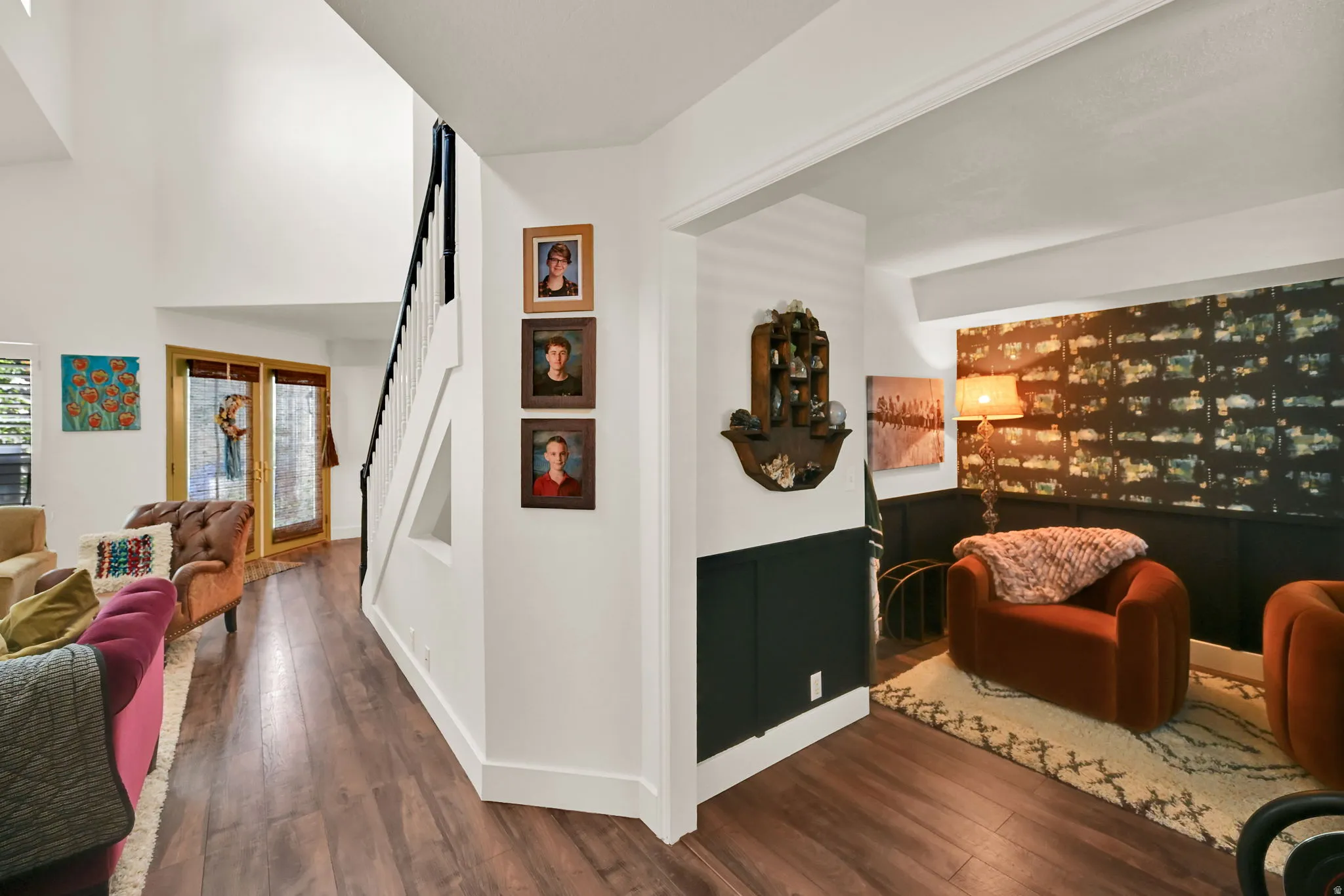 Open-concept living area showcasing hardwood flooring, white painted walls, and vaulted ceilings with exposed beams