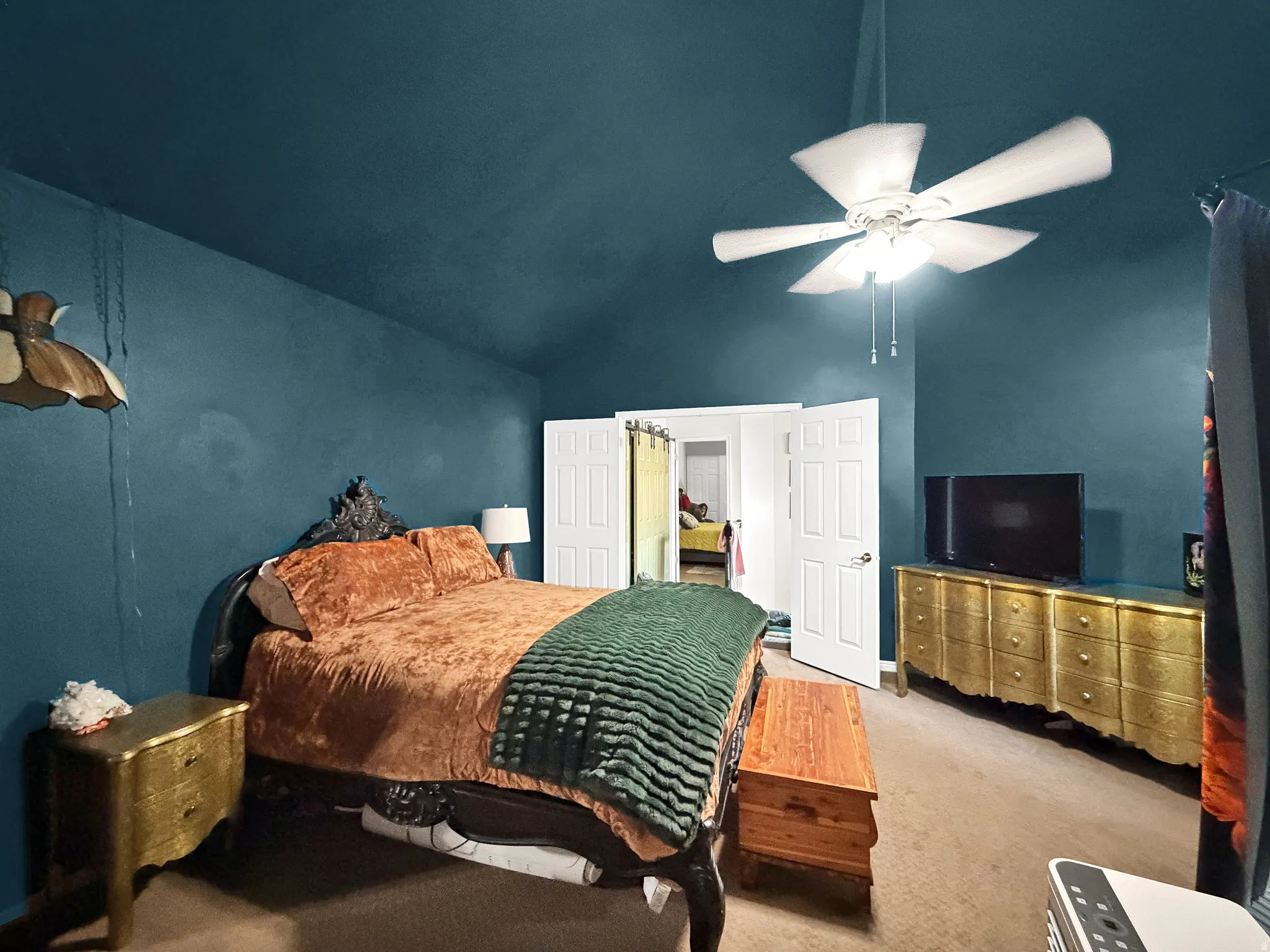 Vaulted ceiling with a ceiling fan, carpet flooring, and paneled interior doors