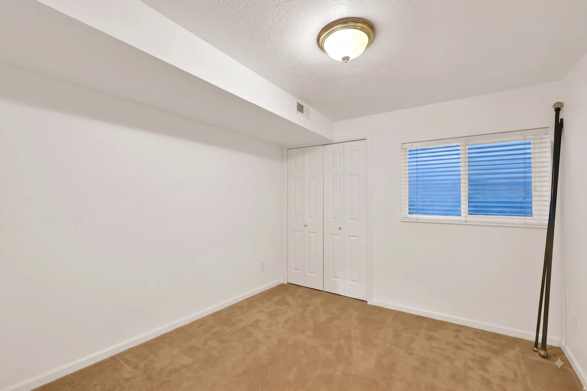Bright secondary bedroom showcasing neutral wall finishes, wood-finish flooring throughout, and abundant natural light from dual windows