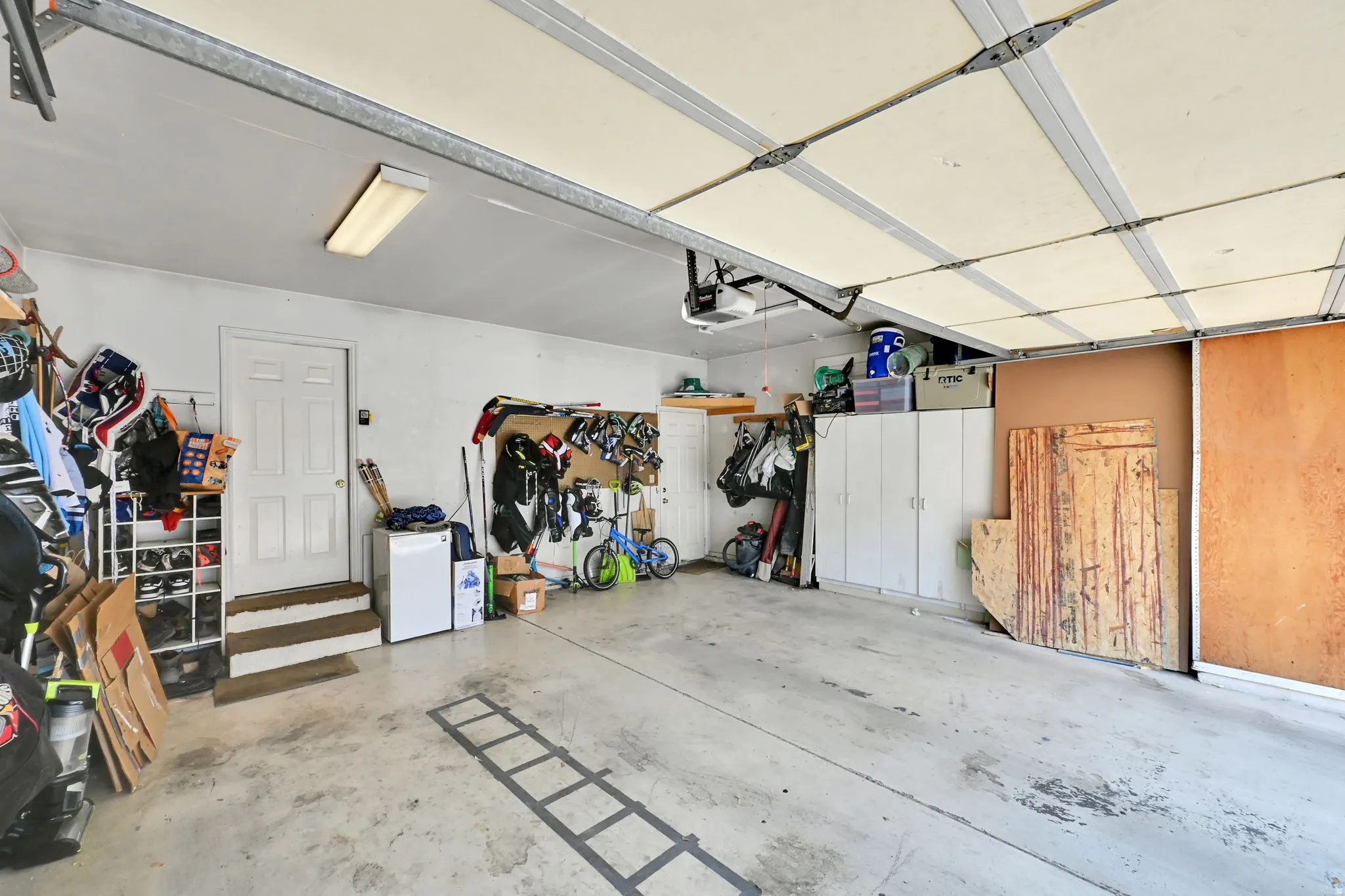Attached garage with concrete flooring, overhead lighting, and built-in storage cabinetry