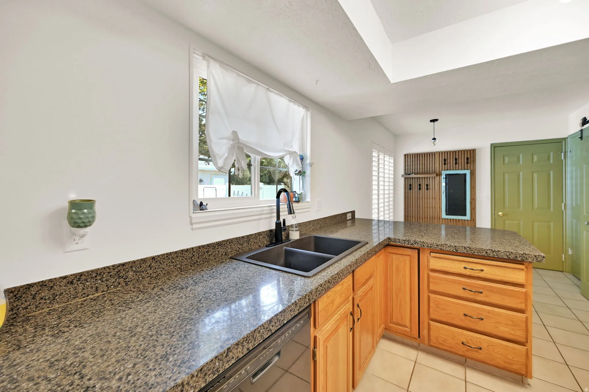 Granite-finish countertops with a built-in double basin sink, wood cabinetry, and tiled flooring