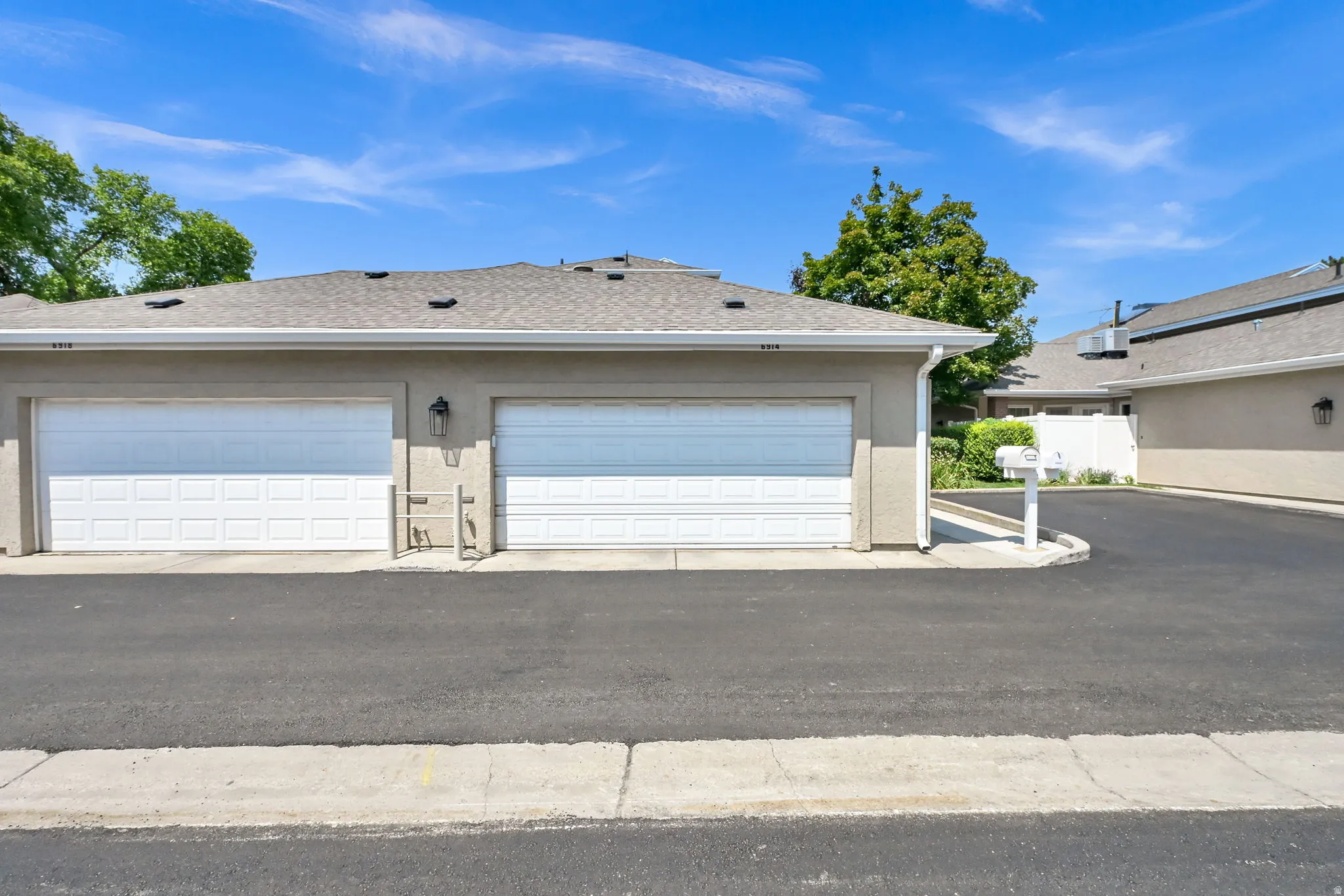 Dual-bay garage featuring white panel doors with horizontal detailing and asphalt driveway apron