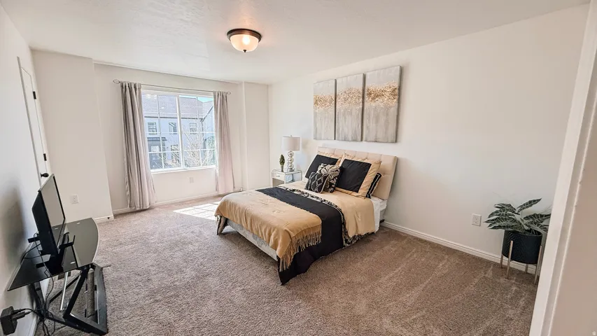 Carpeted flooring, window with natural light, recessed ceiling light, white walls, and a white door with black hardware
