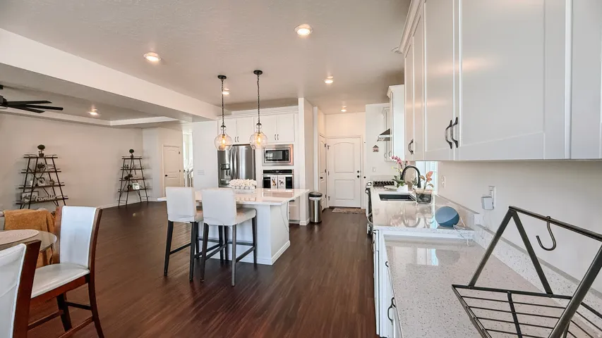 Spacious kitchen with white cabinetry, stainless steel appliances, a large island with seating, and wood-finish flooring