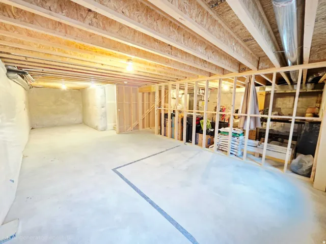 Unfinished basement featuring exposed wood joists, concrete flooring, and partial wood framing