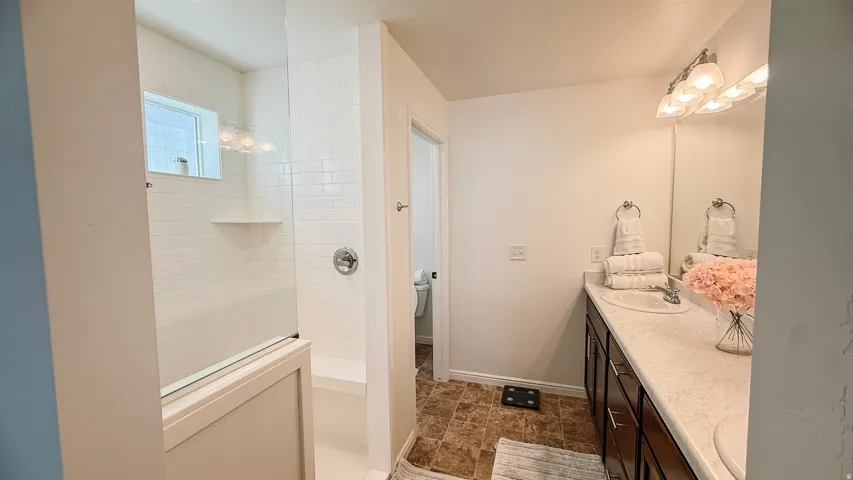Bathroom featuring a tile-surround shower with glass enclosure, built-in shower bench, and a window for natural light