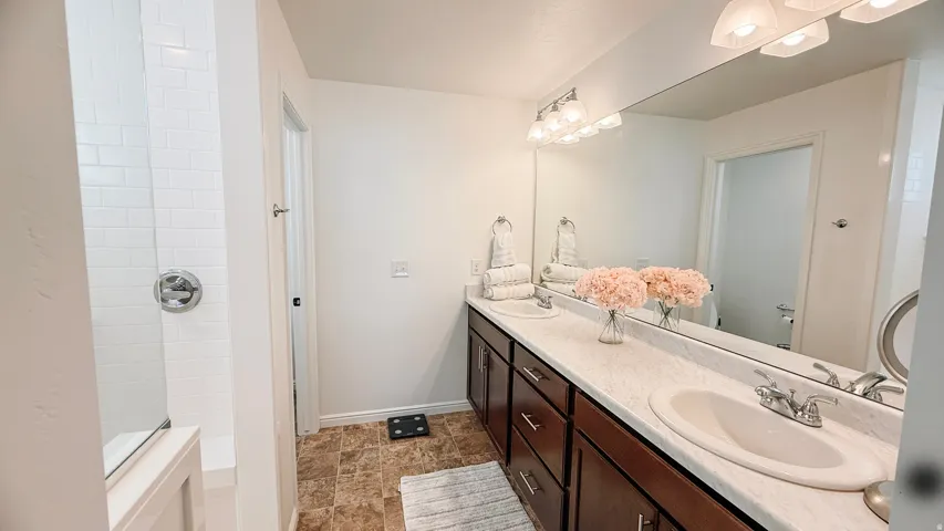 Dual vanity with integrated sinks, ample countertop space, a large wall-mounted mirror, and a 4-light fixture