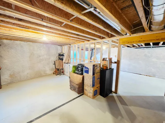 Unfinished lower level featuring exposed ceiling joists, framed partition walls, and concrete flooring