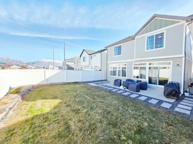 Expansive backyard featuring a manicured lawn, concrete patio, and privacy fencing