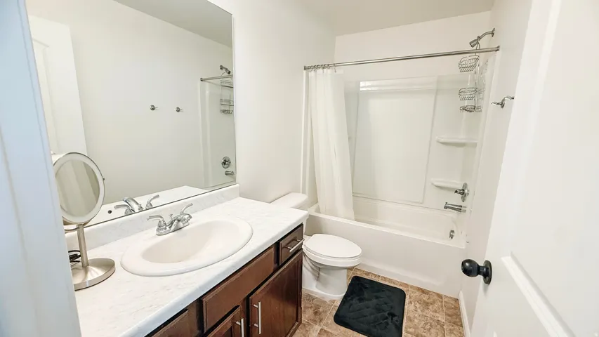 Vanity with integrated sink, wood-finish cabinetry, and a full-width mirror