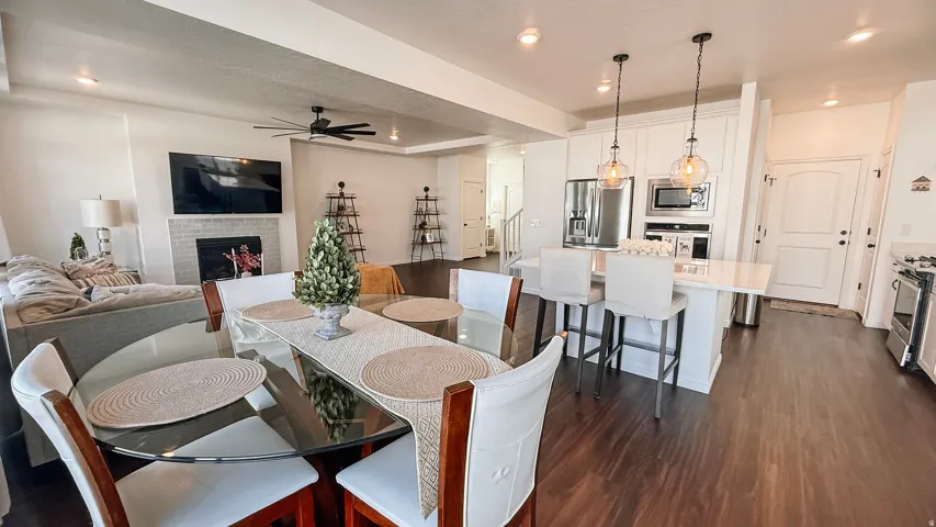Open-concept living area featuring wood-finish flooring, a white brick fireplace, and recessed lighting