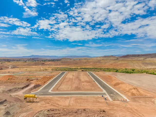 Graded lot with paved road infrastructure, surrounded by a natural desert landscape and distant mountain ranges