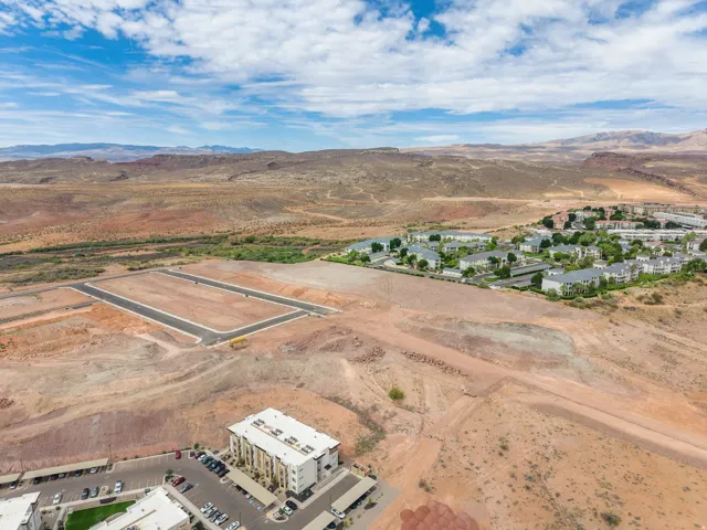 Expansive undeveloped land, graded lots with paved access, established residential developments, and distant mountainous terrain