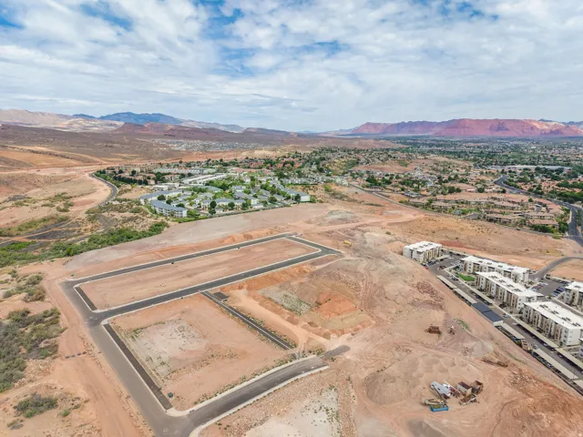 Expansive land parcels with established road infrastructure, surrounded by distant mountains and existing residential developments