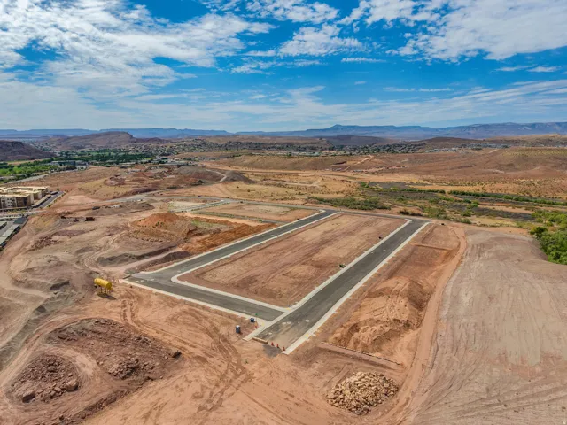 Expansive development site with newly paved roads, visible building pads, and distant mountainous terrain