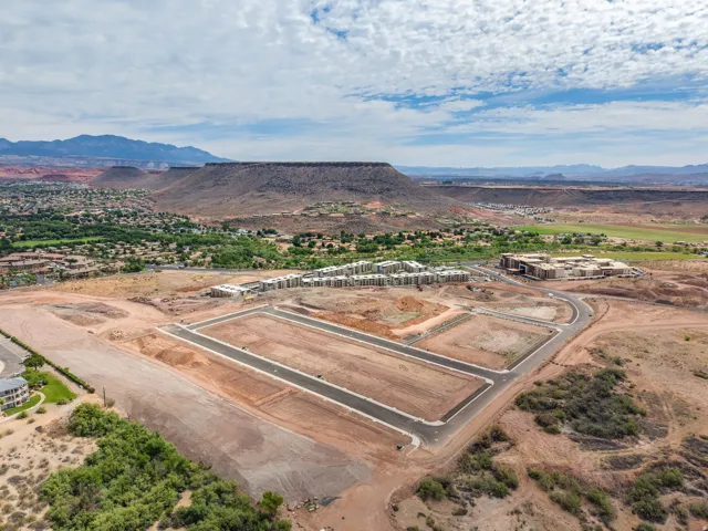 Graded development lots with paved roads, framed by distant mountains and a green valley