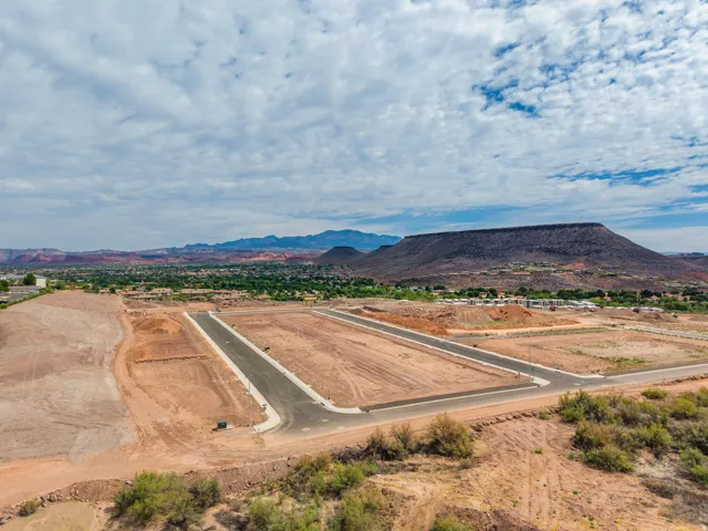 Undeveloped land featuring paved roads and utilities, surrounded by natural desert topography and distant mountain ranges