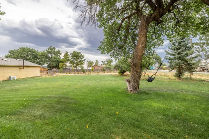 Expansive green lawn with mature trees and a fenced perimeter