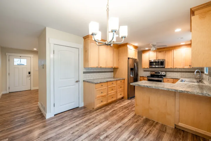 Wood-finish flooring, recessed lighting, shaker-style cabinetry, stainless steel appliances, and stone countertops