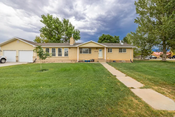 Brick exterior with an attached two-car garage, mature front yard trees, and a concrete pathway leading to the entry