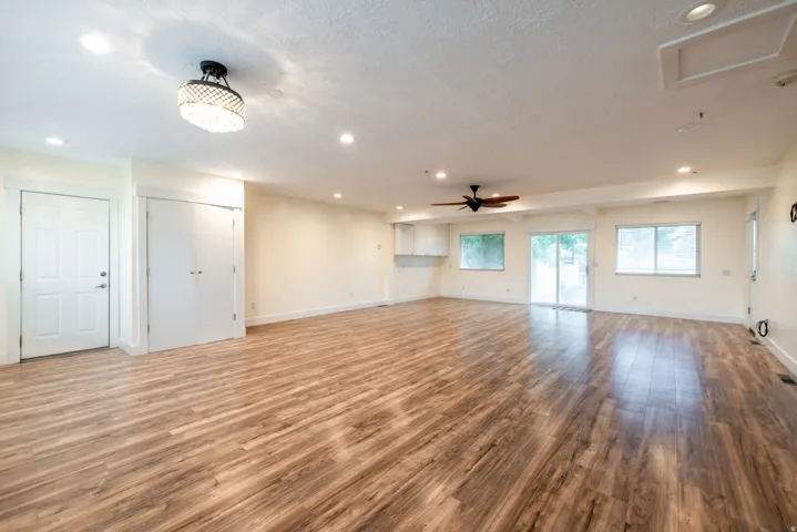 Spacious open-concept living area featuring hardwood flooring throughout, recessed ceiling lighting, and multiple windows providing natural illumination