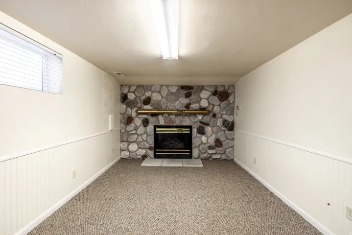 Stone-faced fireplace with a metal mantel, electric insert, and white tile hearth