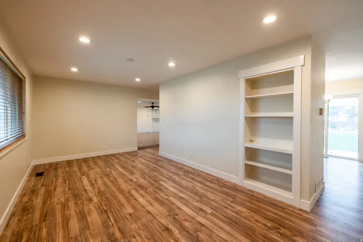 Recessed lighting, wood-finish flooring, built-in shelving, white trim, and a sliding glass door