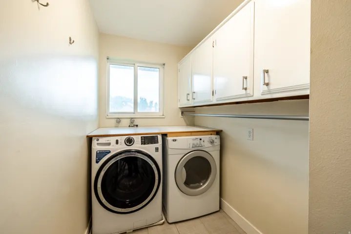 Laundry area featuring a window, built-in cabinetry, an integrated sink, and a hanging rod