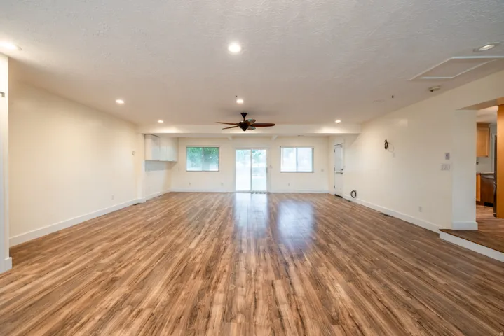 Spacious room featuring wood-finish flooring, recessed lighting, and a ceiling fan