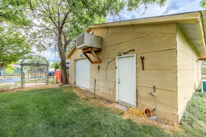Corrugated siding exterior building featuring  a roll-up door, a side entry door, and a wall-mounted air conditioning unit