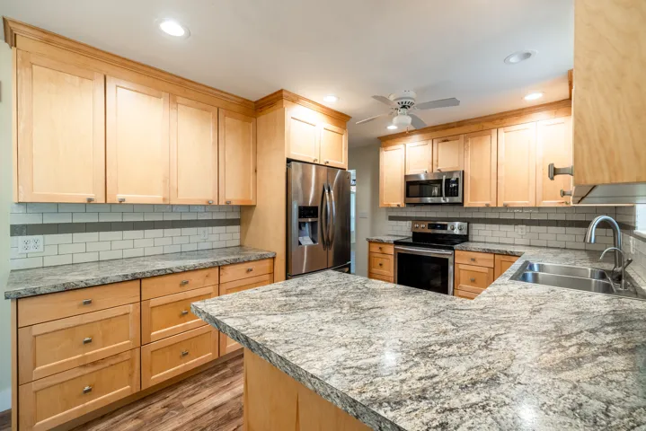 Wood-finish cabinetry, stainless steel appliances, granite countertops, and subway tile backsplash