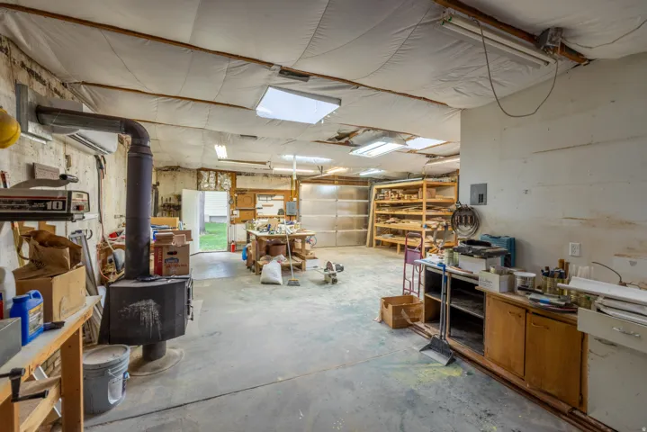 Spacious shop featuring a concrete floor, built-in shelving, wood-burning stove, and overhead skylights, R-38 insulation.