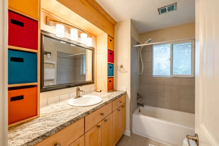 Master bathroom featuring custom wood-finish cabinetry with ample storage, marble-look countertops, and an undermount sink