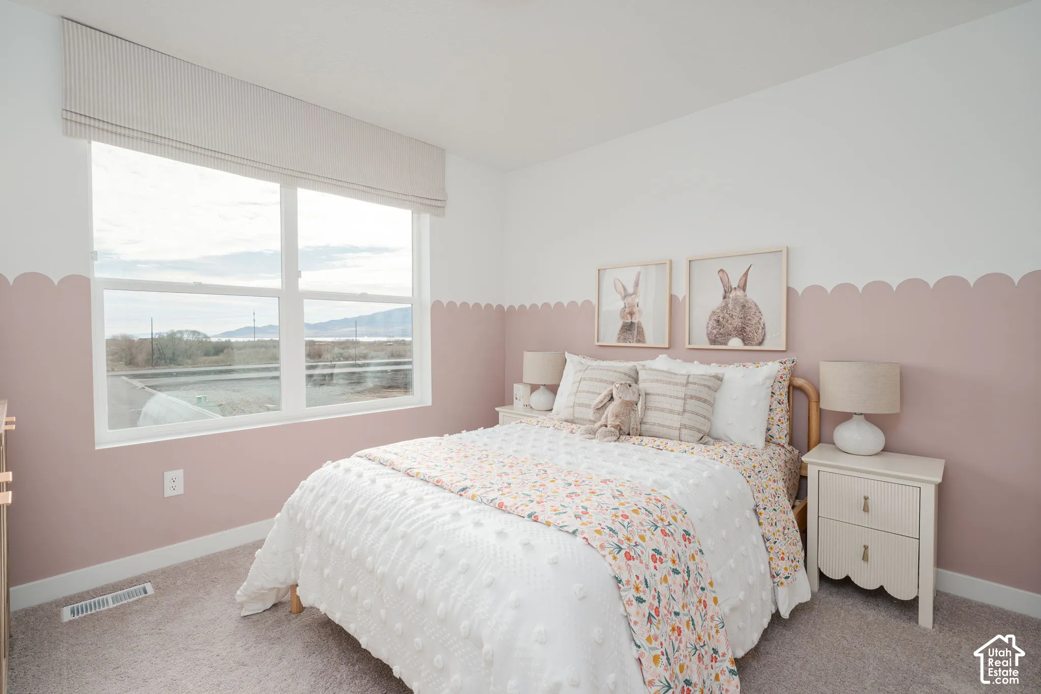 Large picture window with custom window treatment, two-tone painted walls with scalloped detail, and carpeted flooring