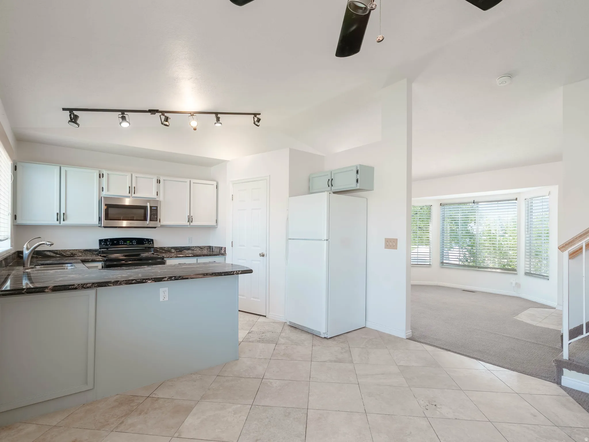 Kitchen featuring light-finish cabinetry, dark countertops, and stainless steel microwave