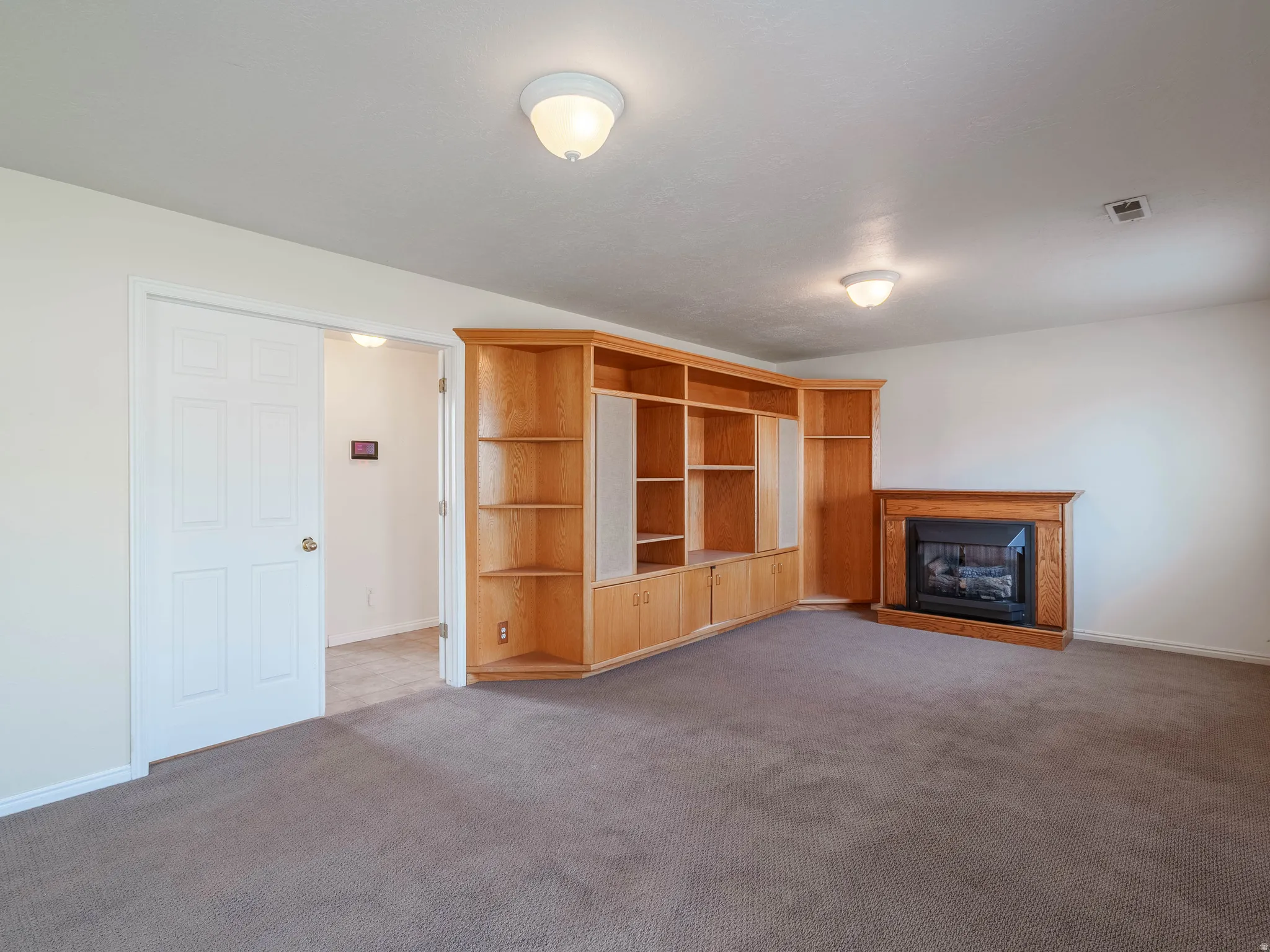 Built-in wood-finish cabinetry, fireplace with wood-finish mantel, carpet flooring, and recessed lighting