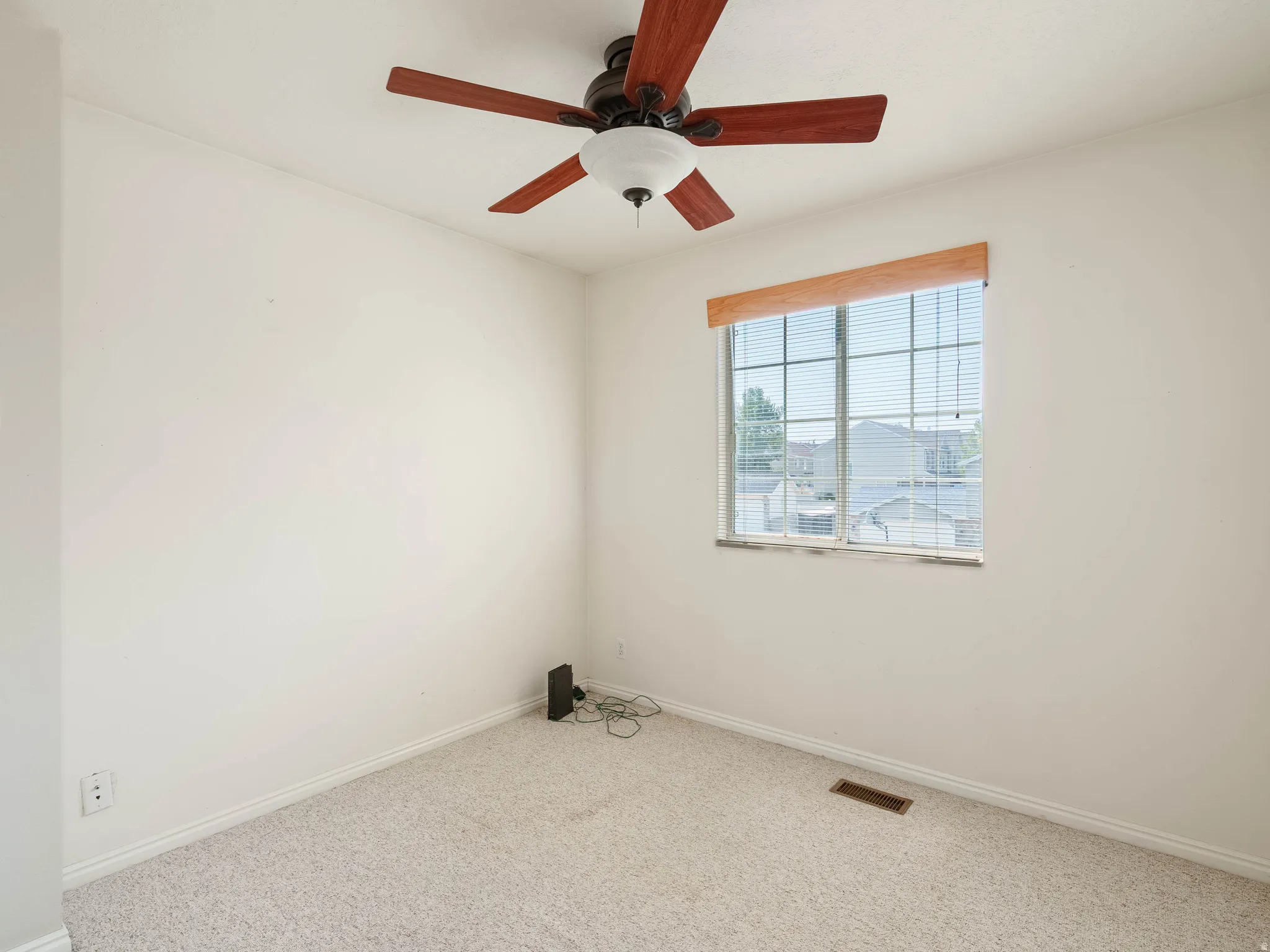 Carpeted flooring, ceiling fan with light fixture, window with blinds, and white walls