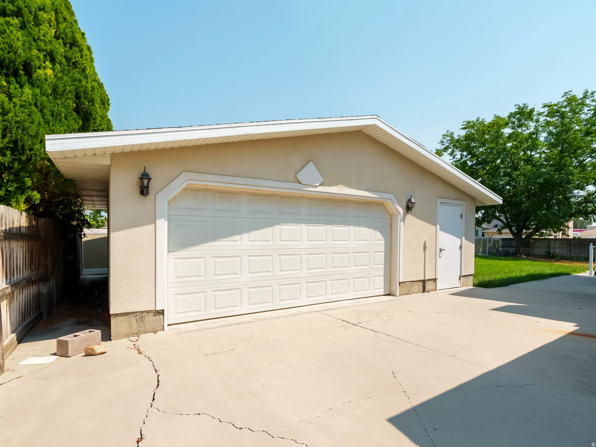 Detached garage featuring a paneled door, exterior lighting fixtures, and a side access door