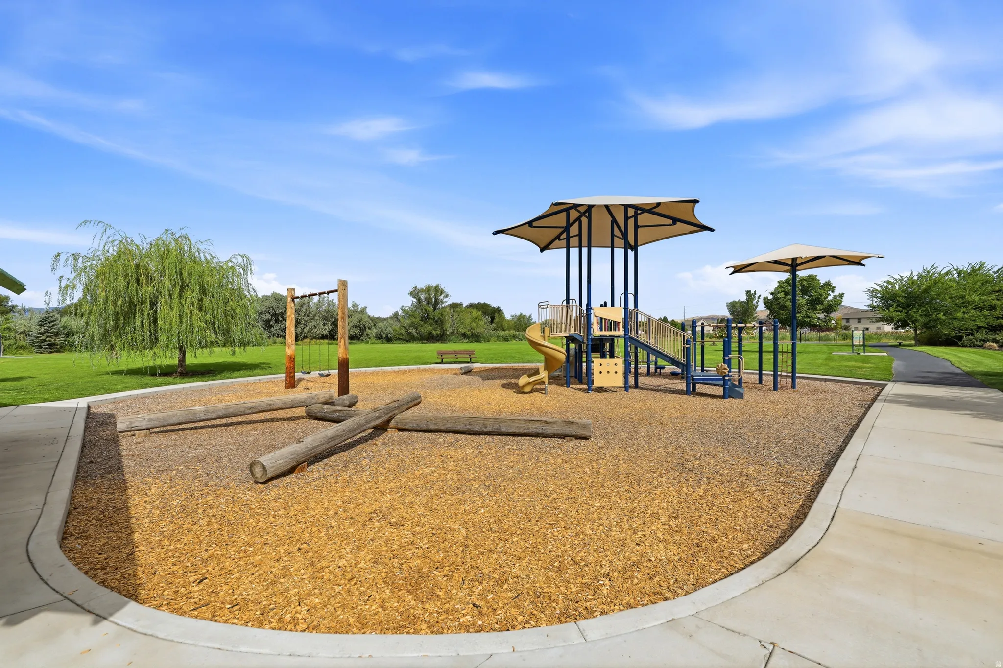 Playground area featuring a play structure with slides, swings, and shade canopies