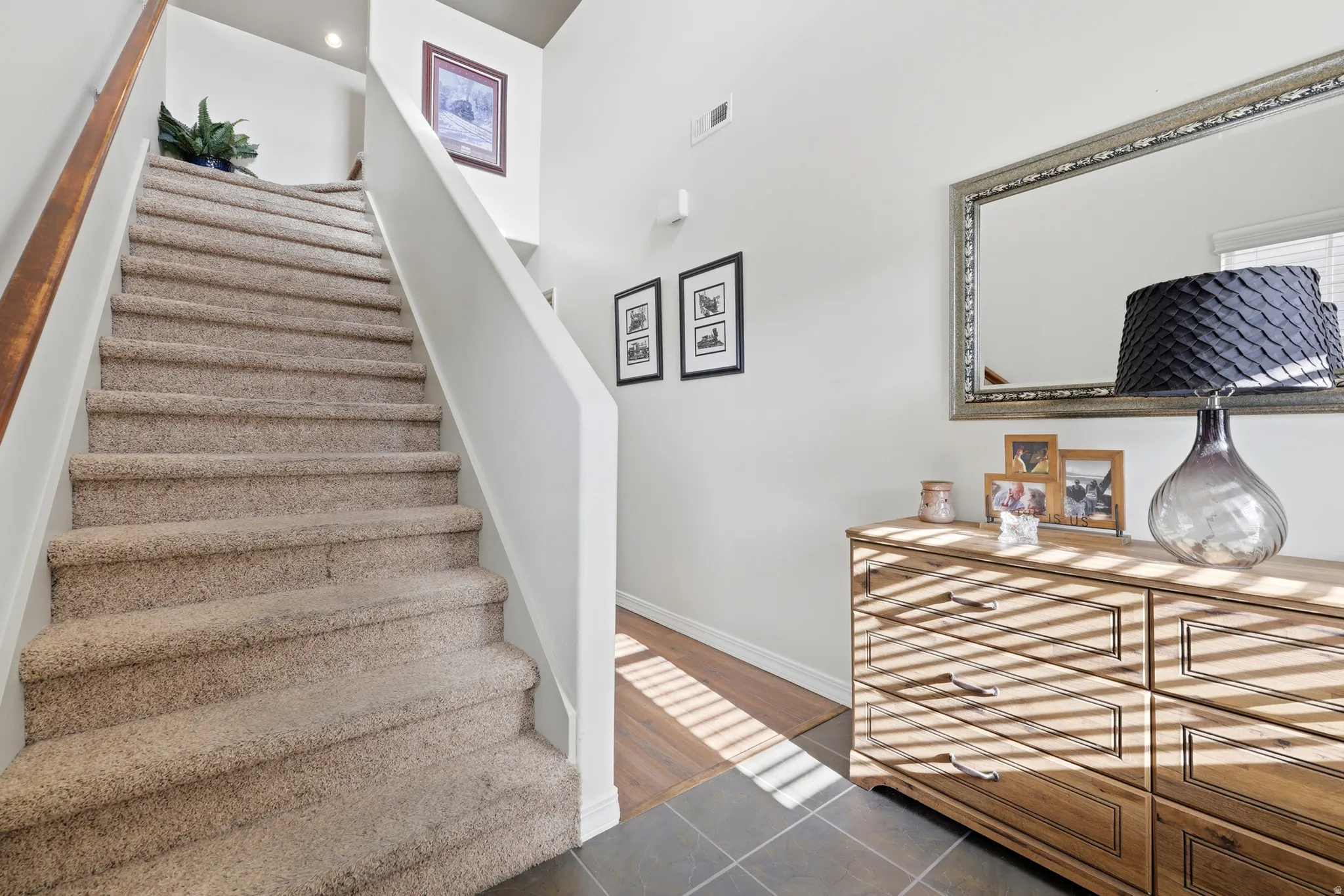 Carpeted staircase with a wood handrail, recessed lighting, and a wood-finish flooring transition