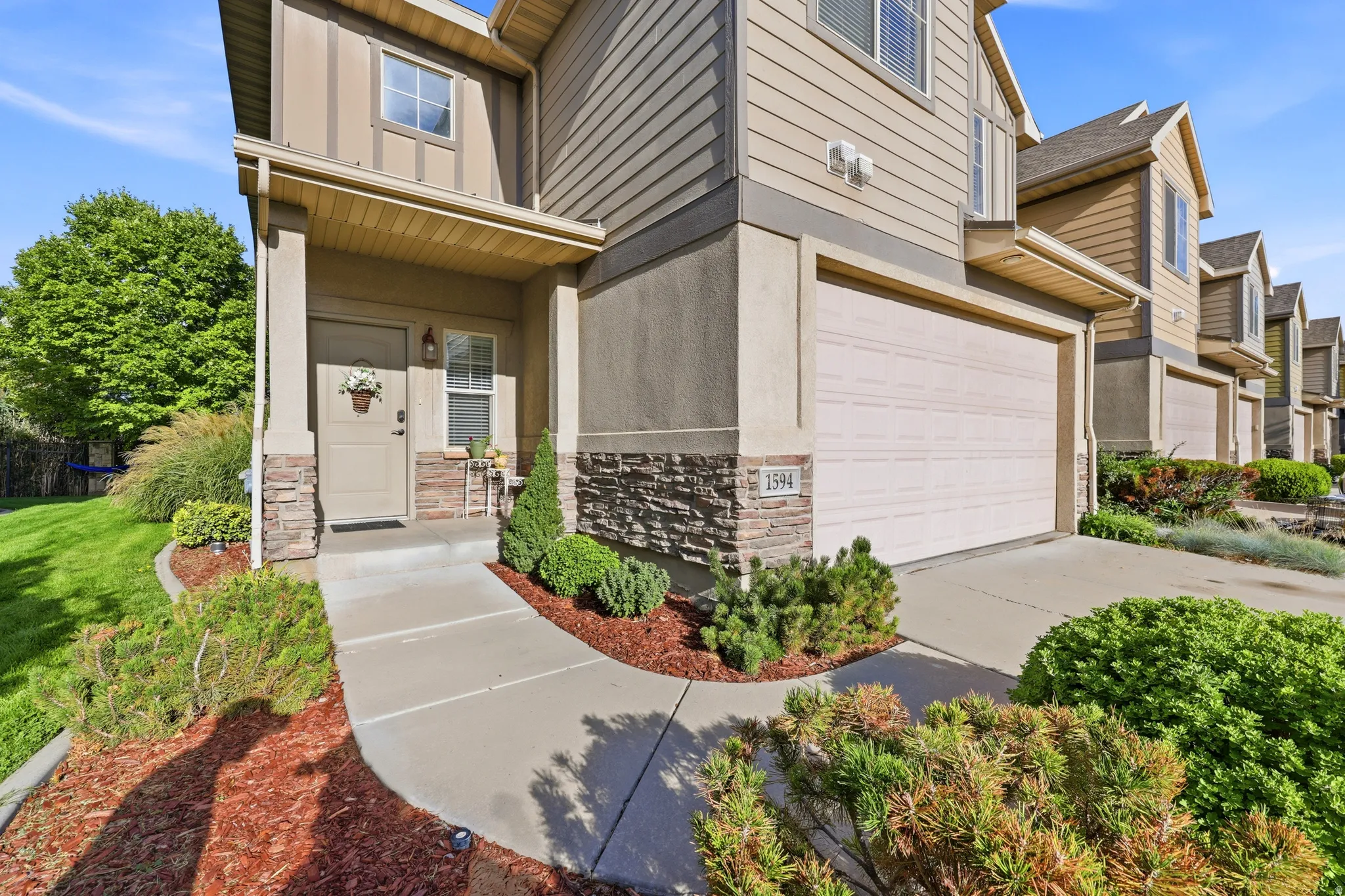 Exterior featuring siding and stone veneer, an attached garage, a covered entry, and a paved walkway
