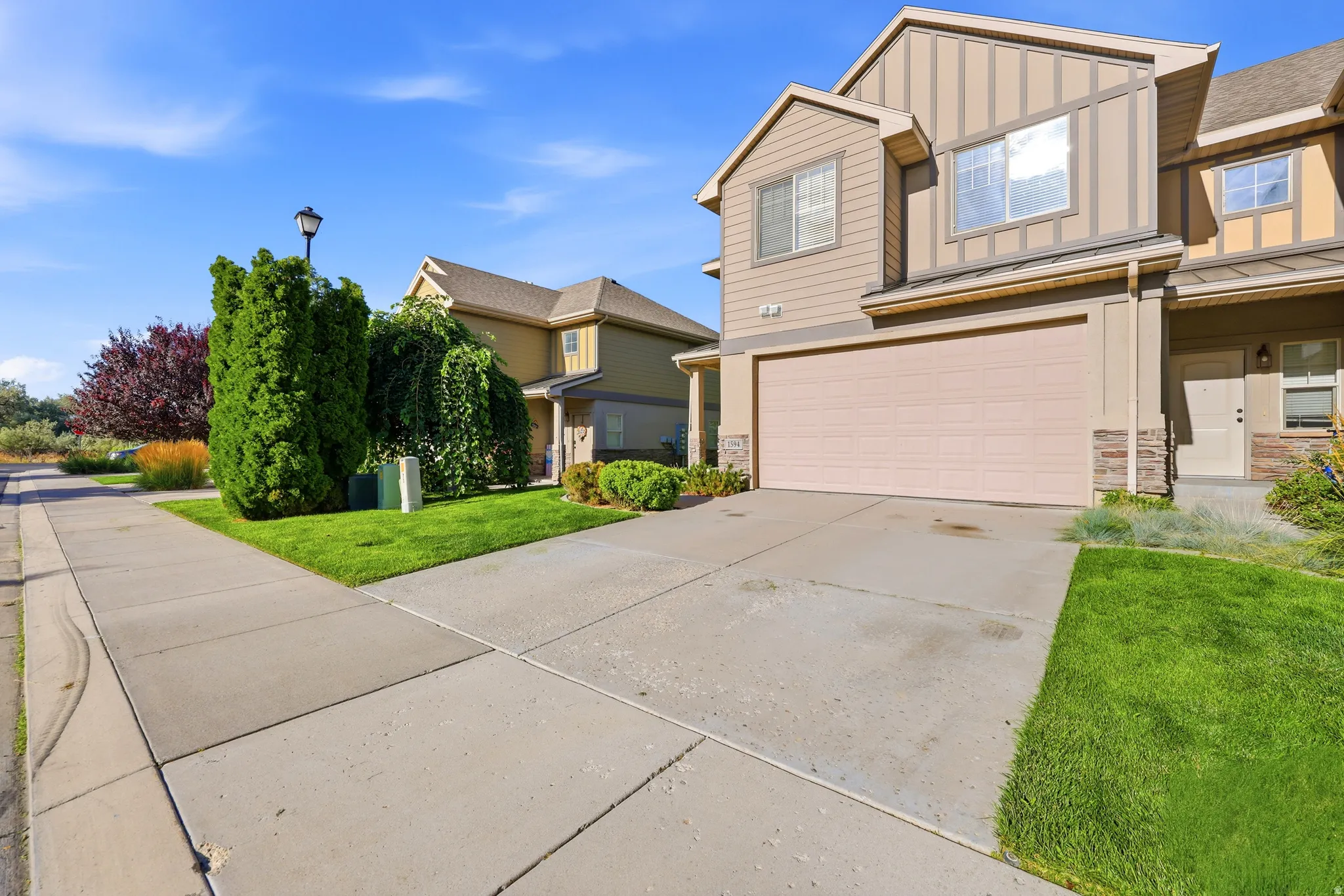 Two-story residence with a two-car garage, stone accents, and a sidewalk